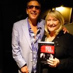 Mike Nicholls with Maggi Ronson. Maggie is holding a copy of My Life with Rock N' Roll People by Mike Nicholls.